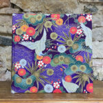 Álbum grande. Tela japonesa. Estampado floral grullas y motivos dorados fondo violeta. Interior Negro.