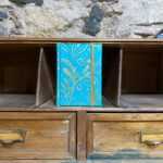 Libreta. Papel. Estampado floral dorado fondo turquesal.