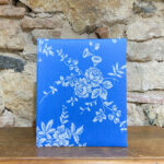Àlbum mitjà. Tela de Damasc o de matalàs. Estampat floral fons blau.